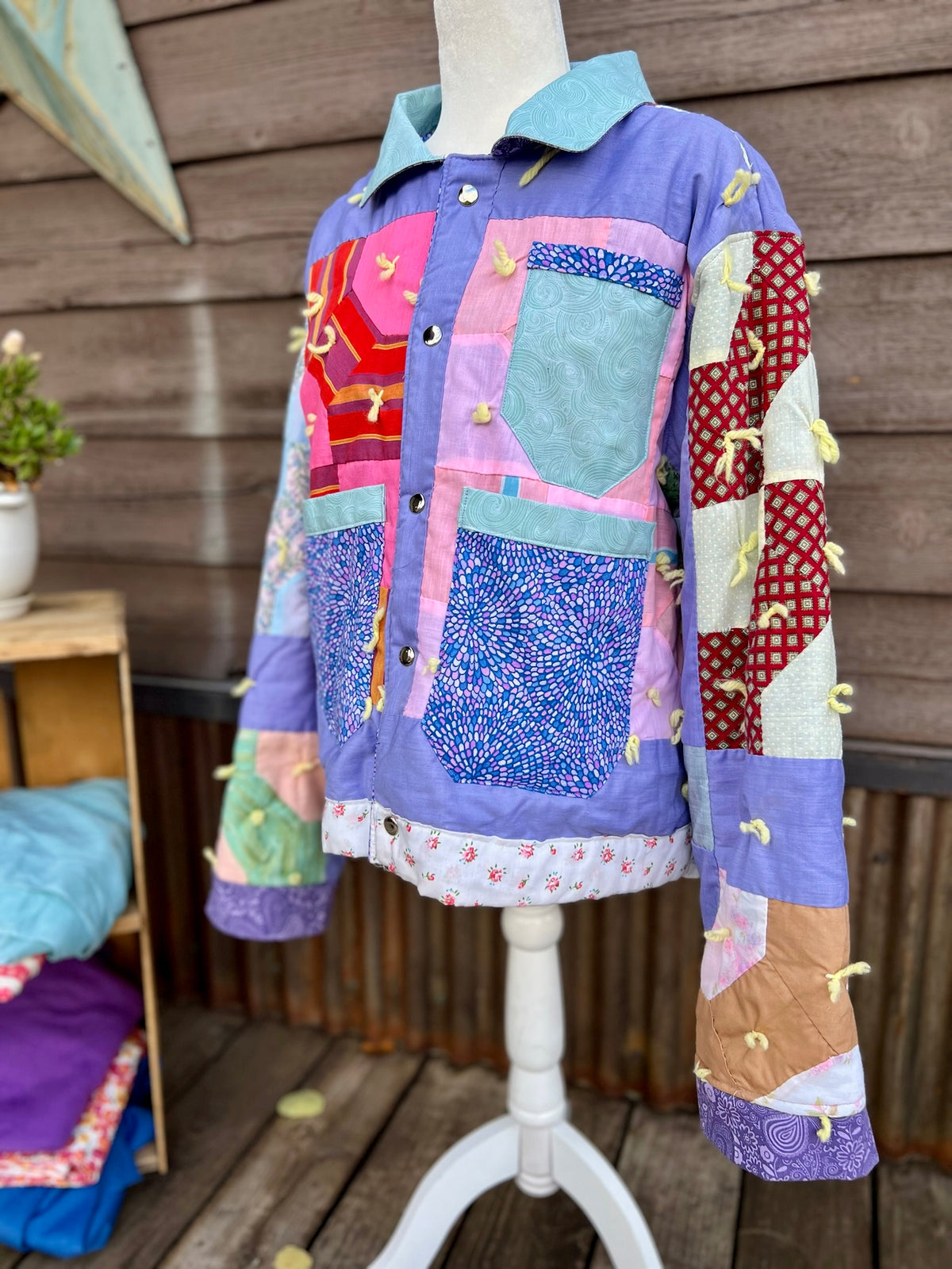 Close-up of the purple pockets and yarn tassels on the purple patchwork vintage quilt camp coat