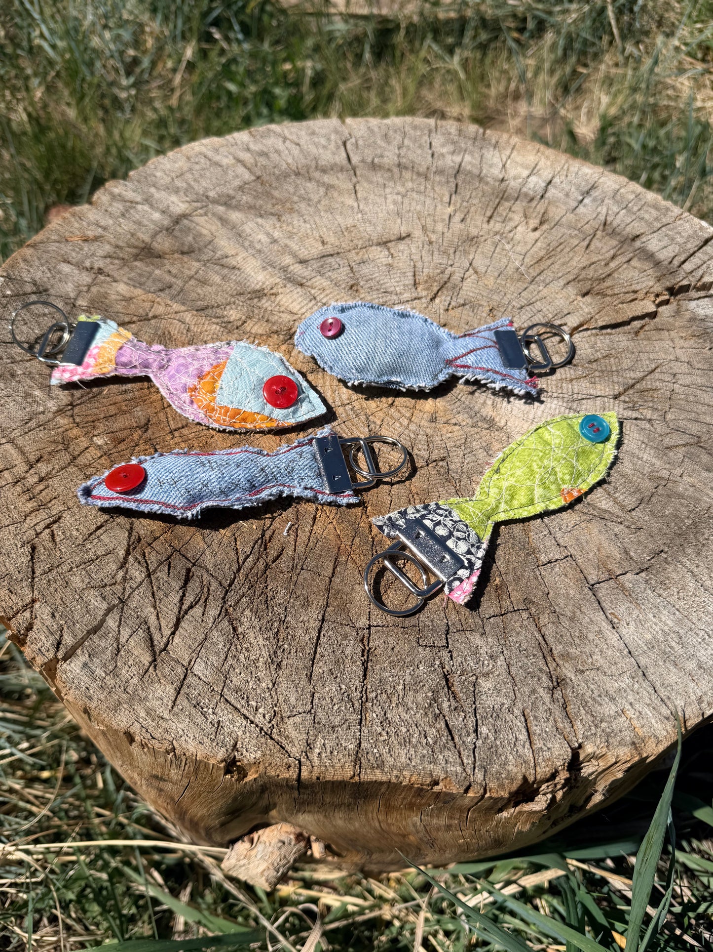 Each fish features a button eye, frayed edges for a rustic handmade feel, and a sturdy metal key fob hardware attachment.