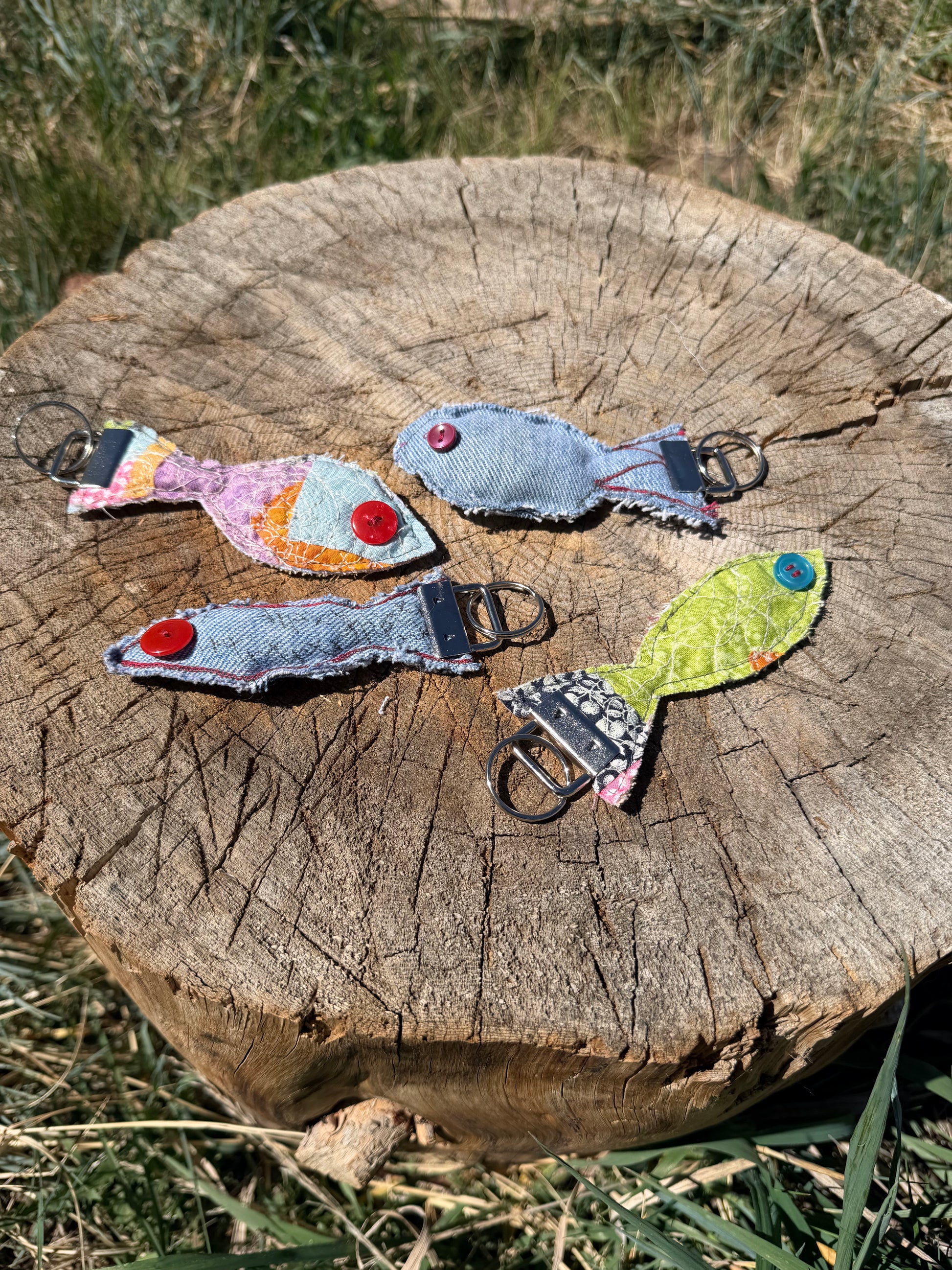 Each fish features a button eye, frayed edges for a rustic handmade feel, and a sturdy metal key fob hardware attachment.
