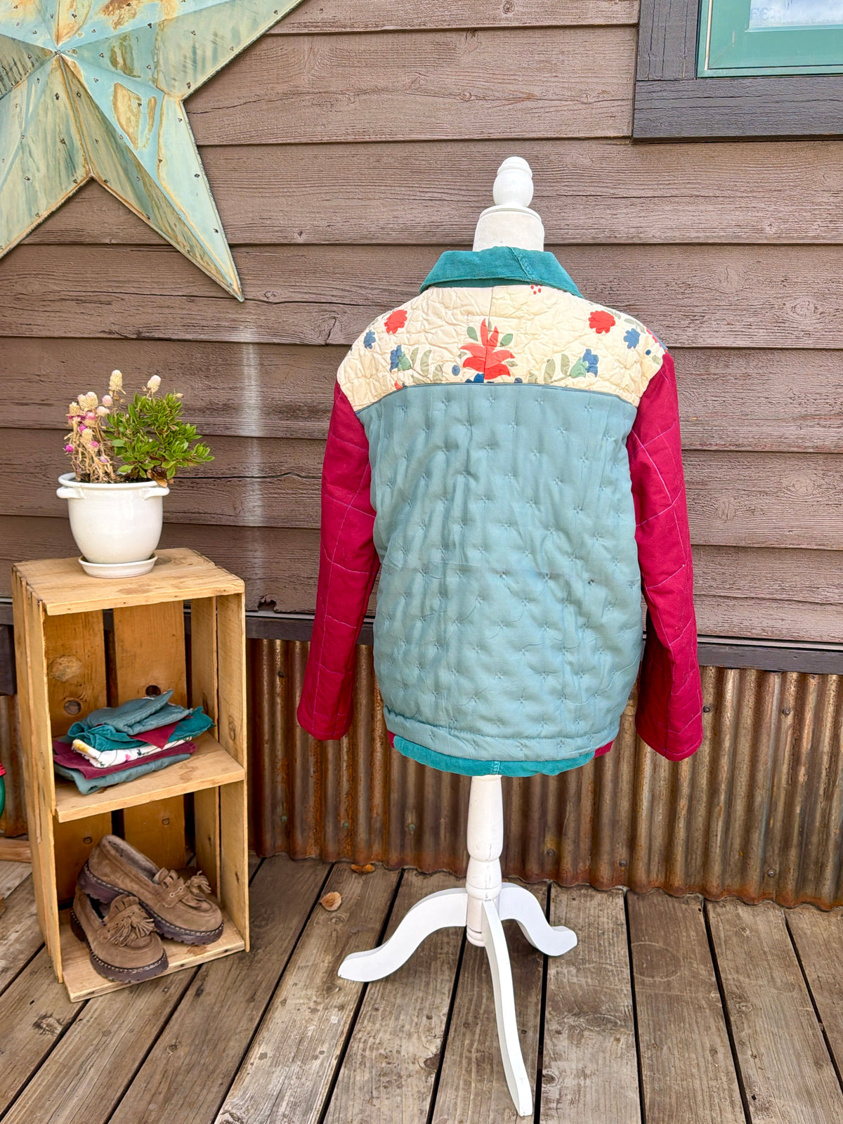 Back of the cream and seafoam floral bedspread camp coat on a mannequin showing the floral and bird print quilted back