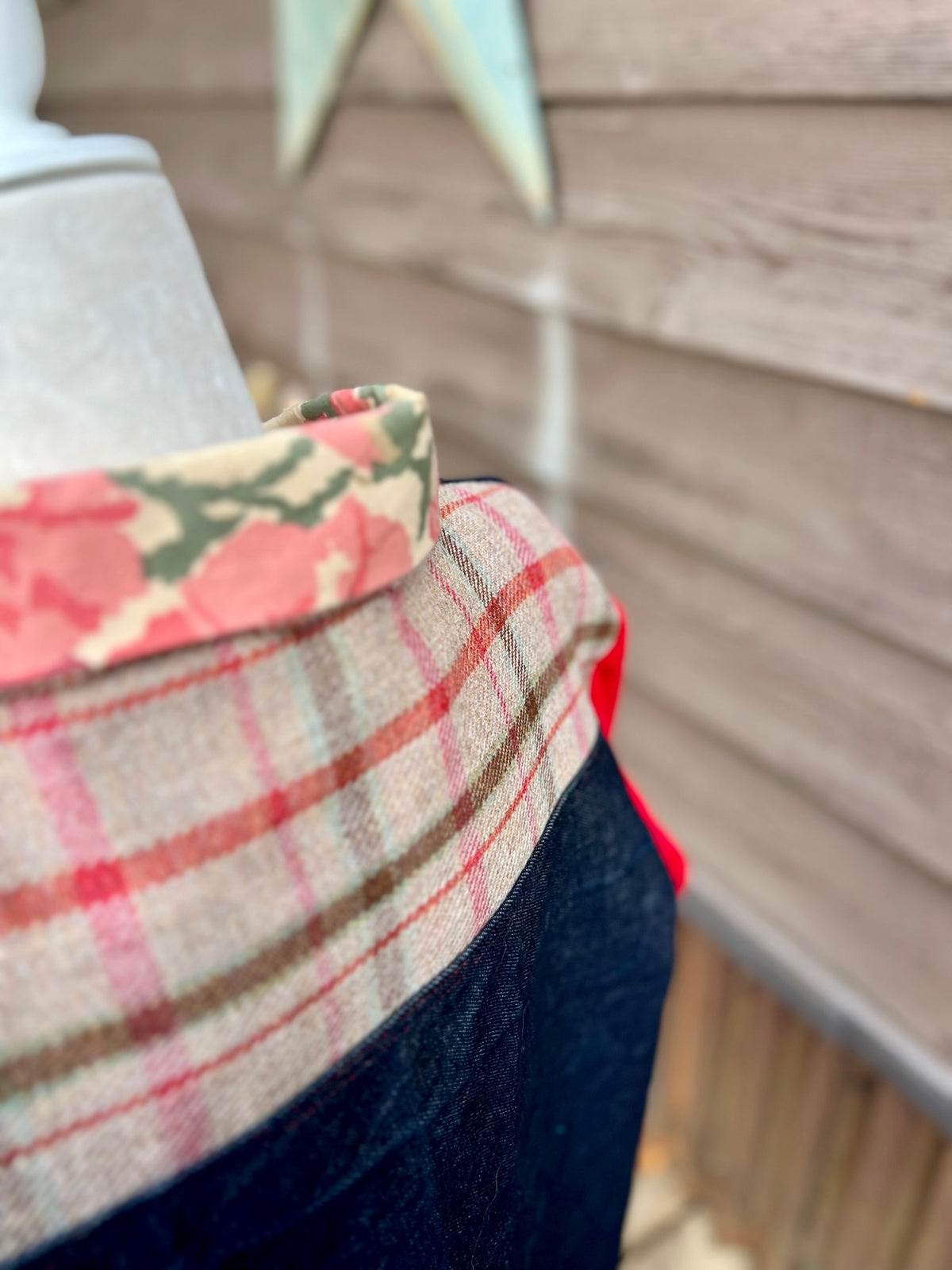 Close-up of the back plaid yoke and floral bedsheet collar on the denim barn coat with red corduroy sleeves