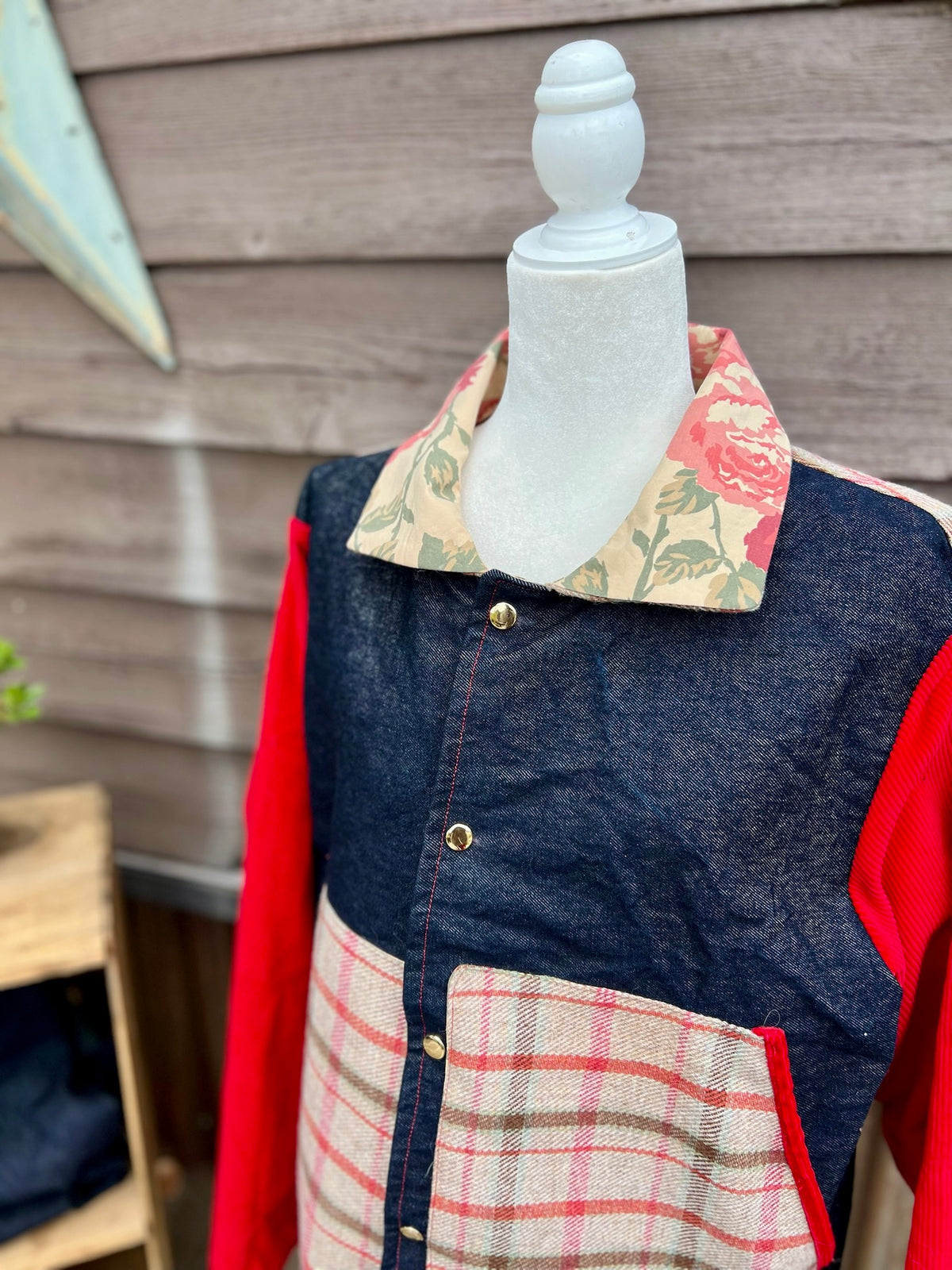 Close-up of the floral bedsheet collar and snap front on the denim barn coat with red corduroy sleeves