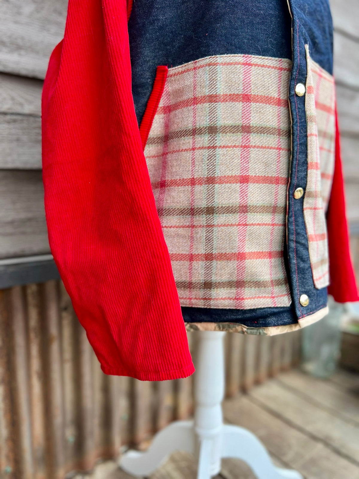 Close-up of the large plaid wool pockets on the denim barn coat with red corduroy sleeves
