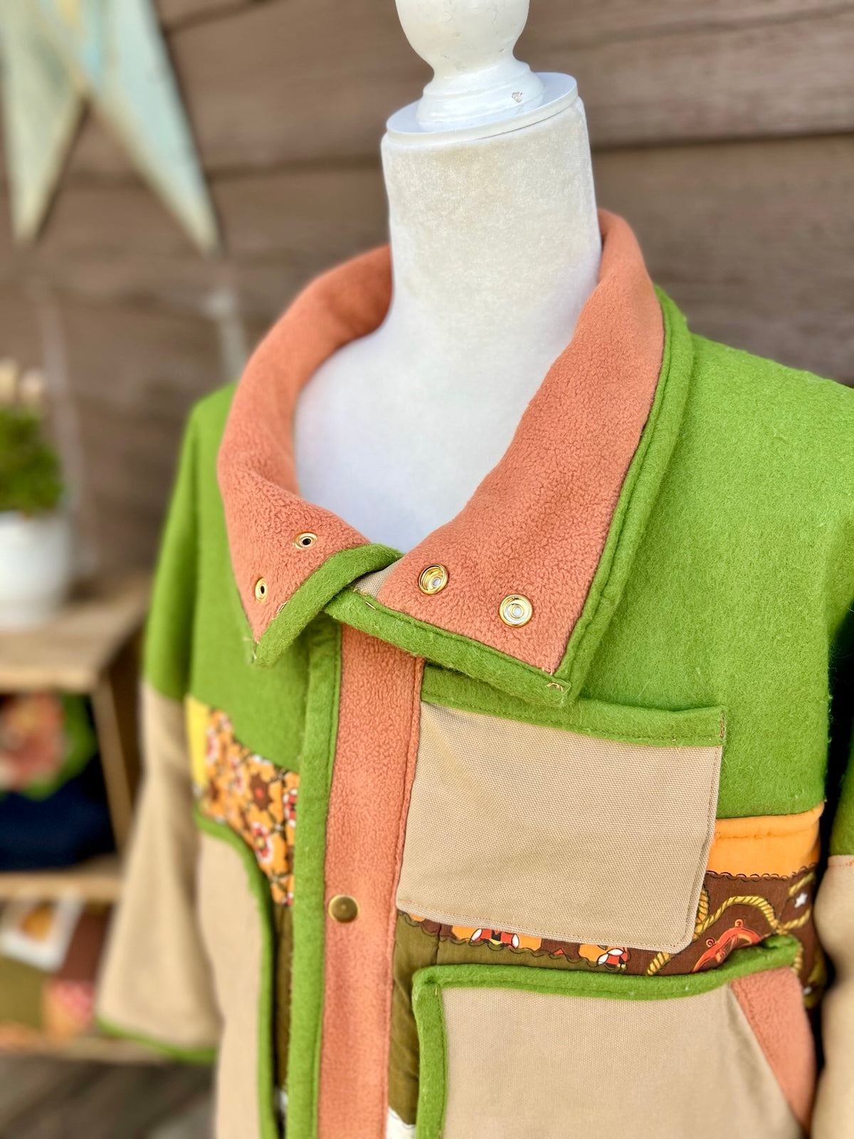  Close-up of the inside lined snap collar, shown folded on the green and tan sleeping bag boxy chore coat