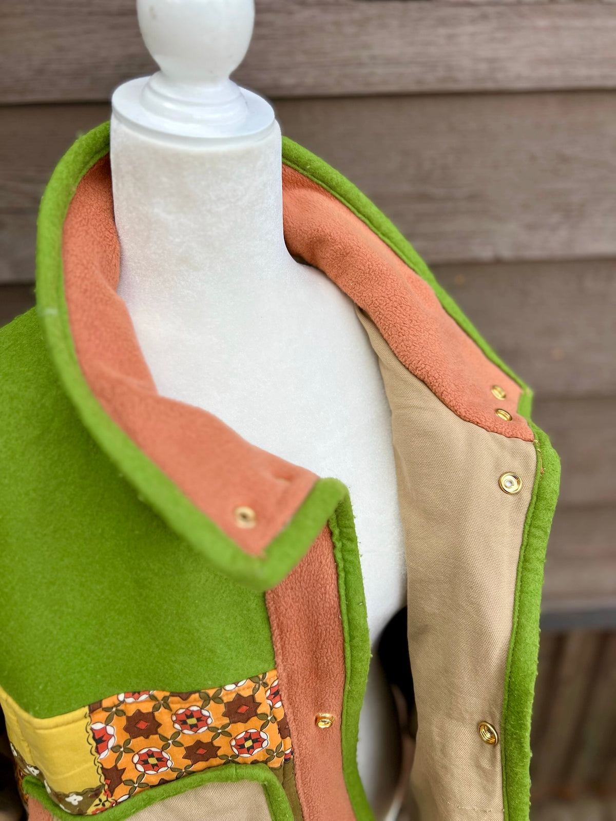  Close-up of the snap collar folded down, shown on the green and tan sleeping bag boxy chore coat