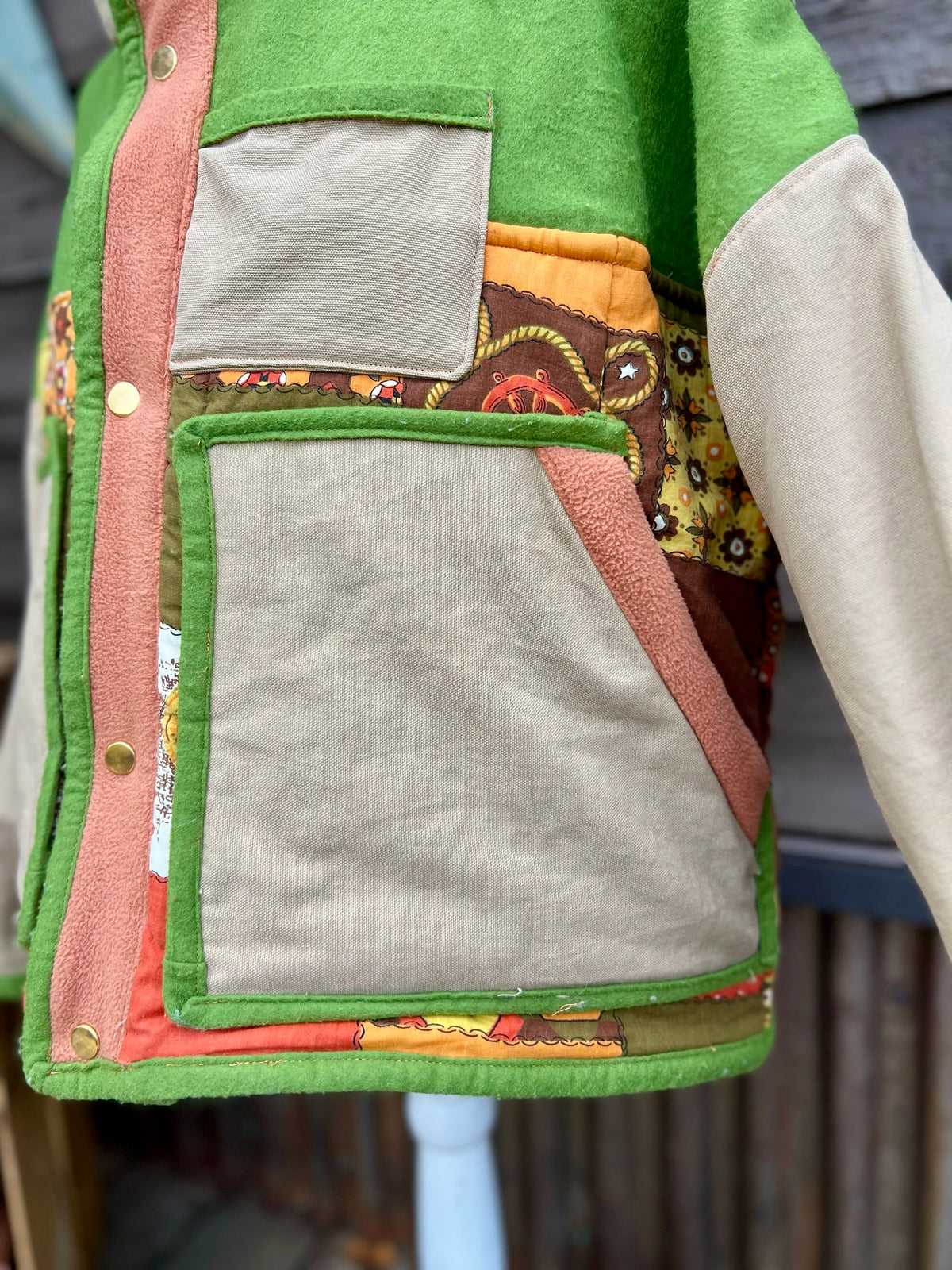 Close-up of the two large front pockets and chest pocket on the green and tan sleeping bag boxy chore coat