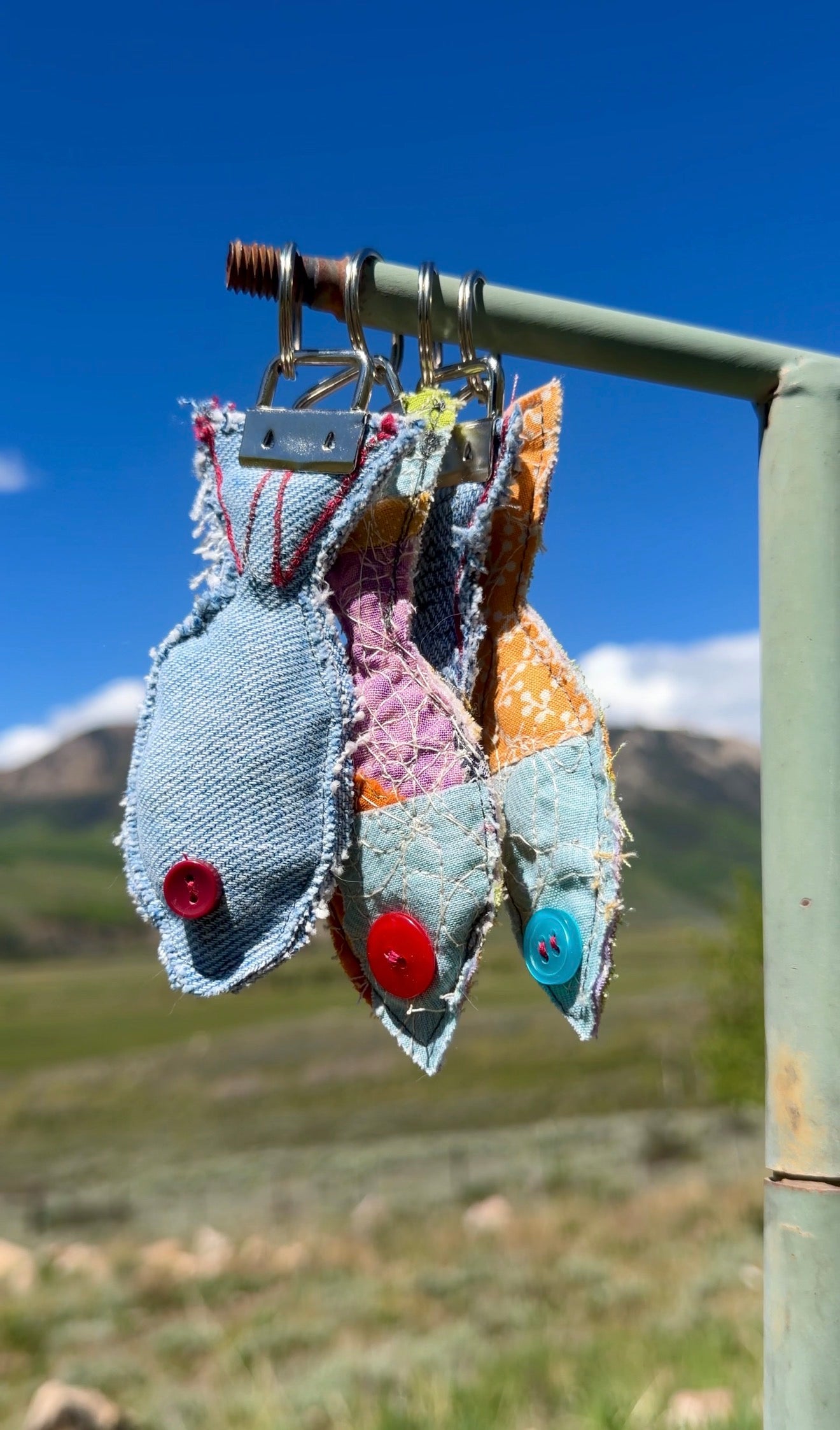 Each fish features a button eye, frayed edges for a rustic handmade feel, and a sturdy metal key fob hardware attachment.