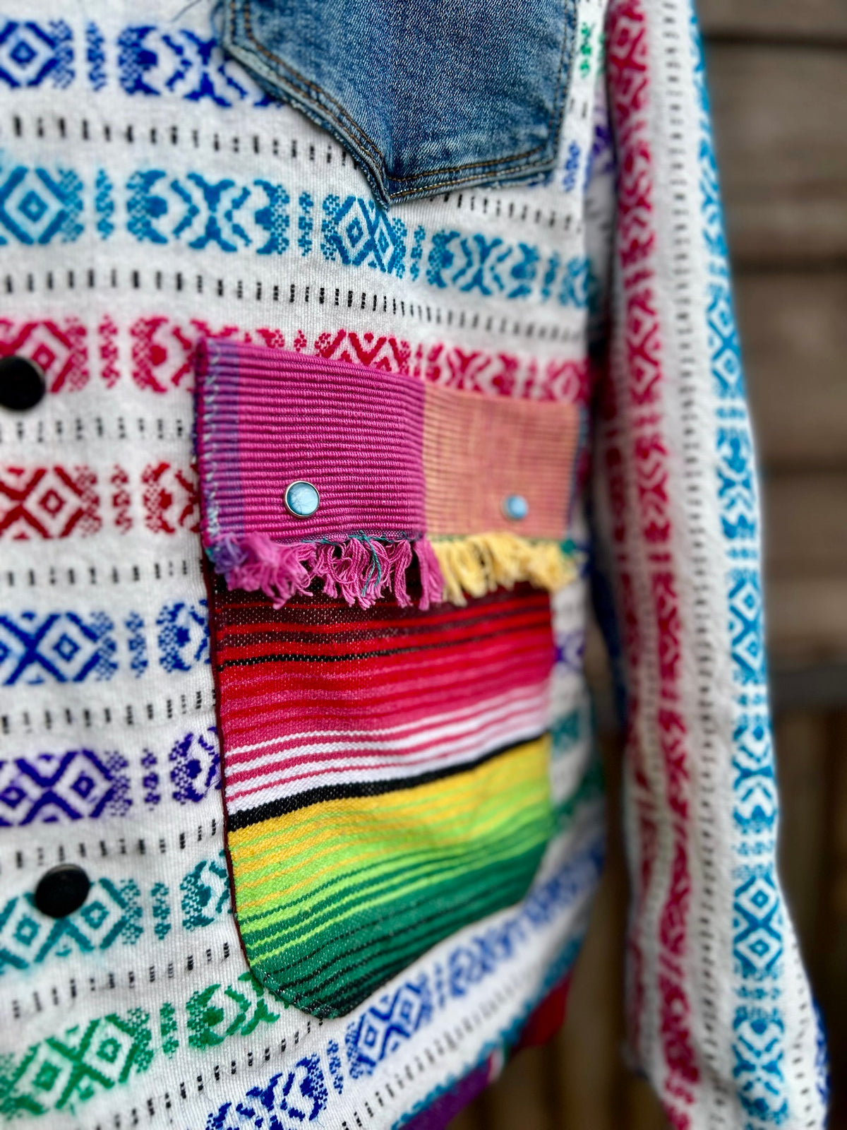 Close-up of the placemat pockets with pearl snaps on the multicolor woven stripe blanket camp coat
