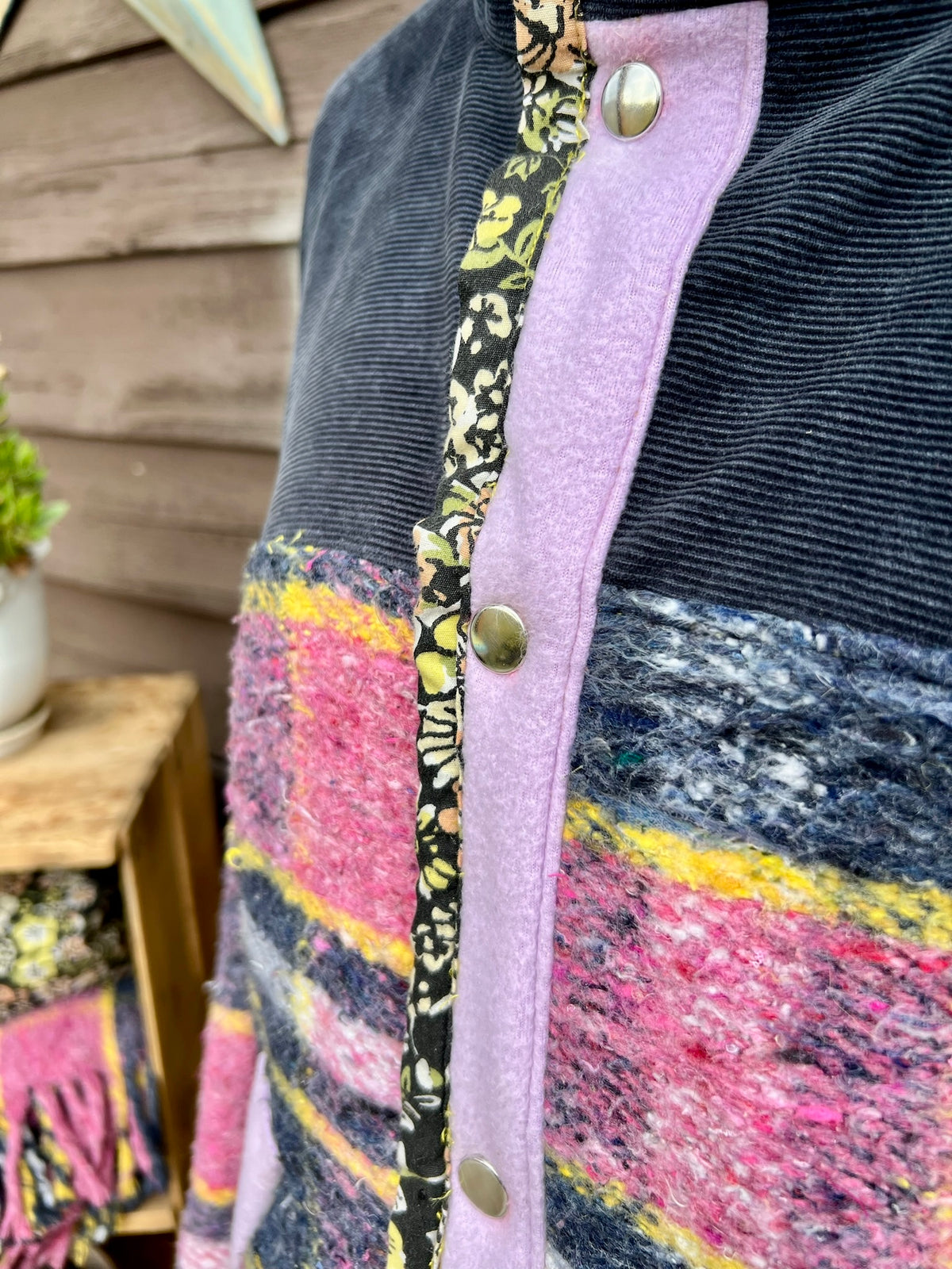 Close-up of closure and placket on pink, yellow, navy and white plaid wool blanket beside navy corduroy on the pink plaid blanket coat