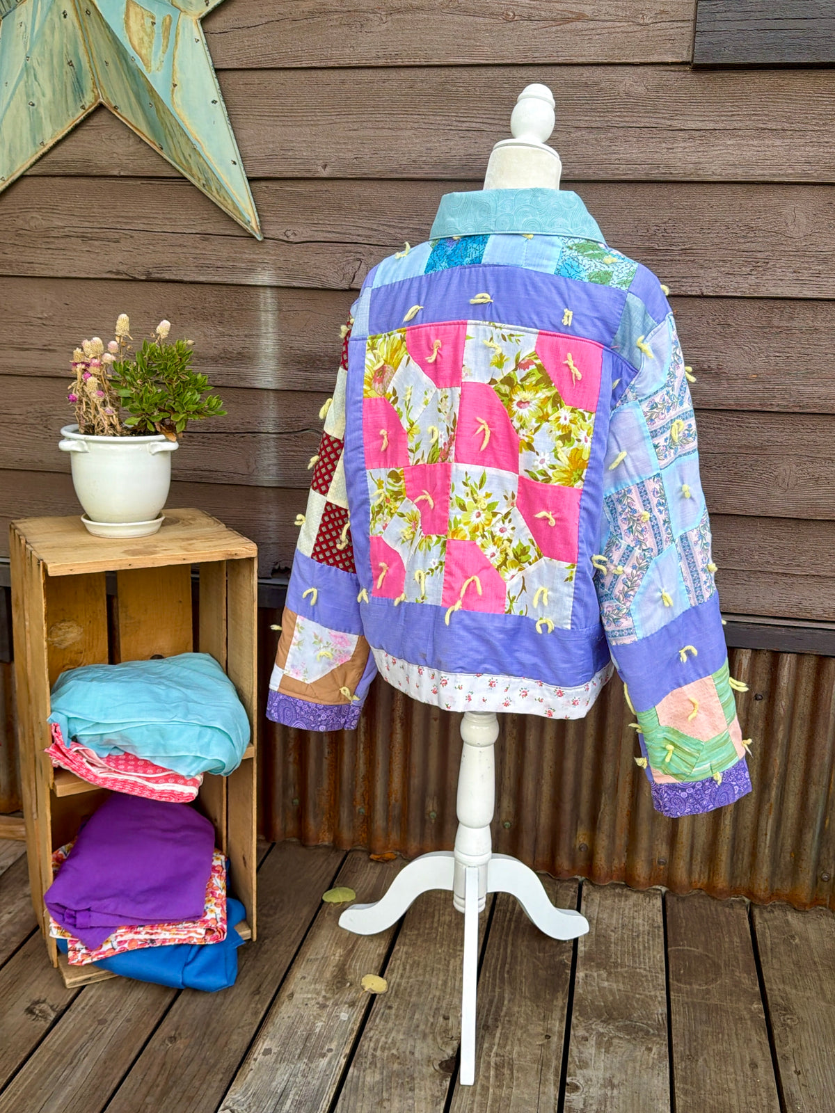 Back of the purple patchwork vintage quilt camp coat on a mannequin showing the purple patchwork quilt back