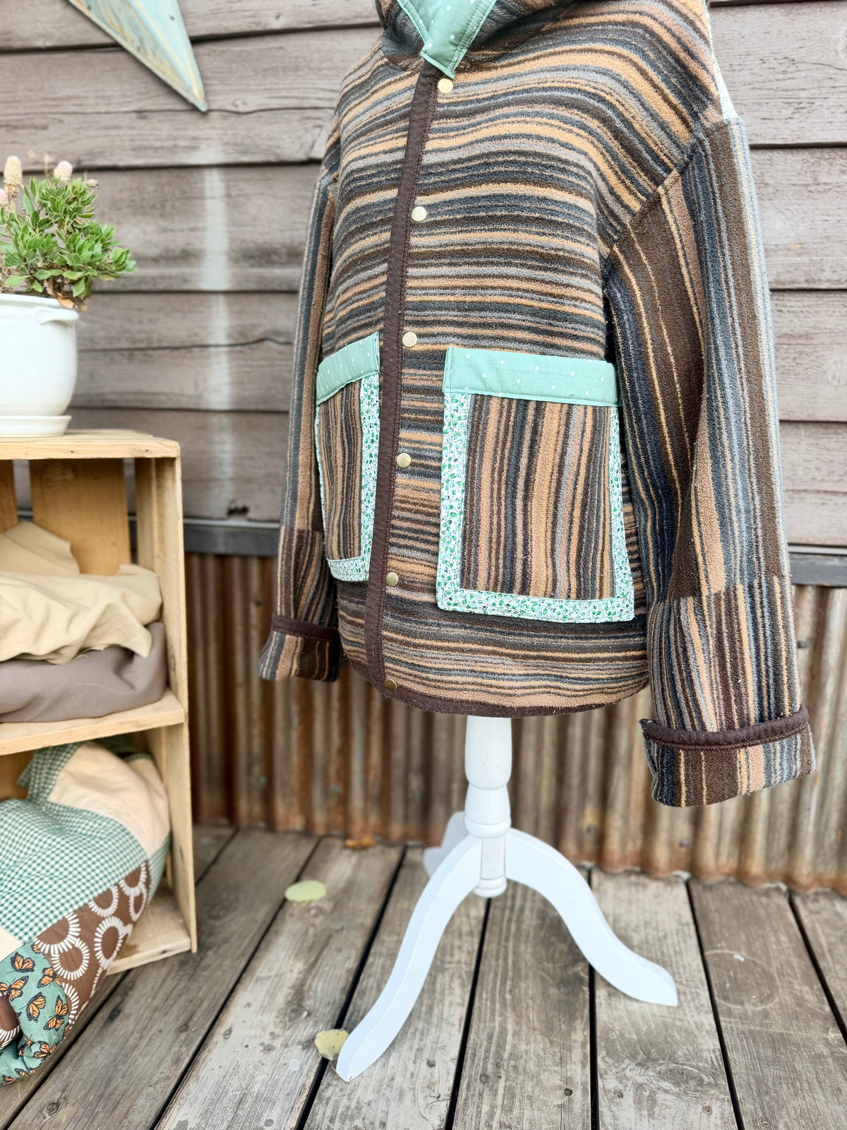 Close-up of the large pockets with polka dot, floral and plaid bias trim on the striped horse blanket hooded coat