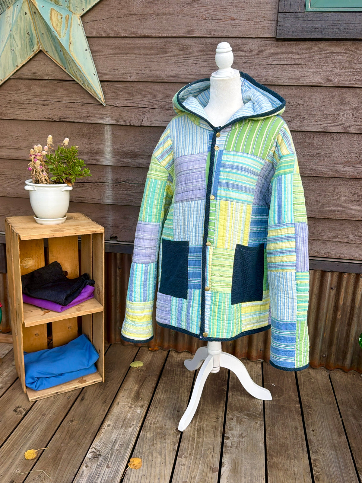 Striped quilt hooded coat in green, yellow, blue and purple on a mannequin, front view