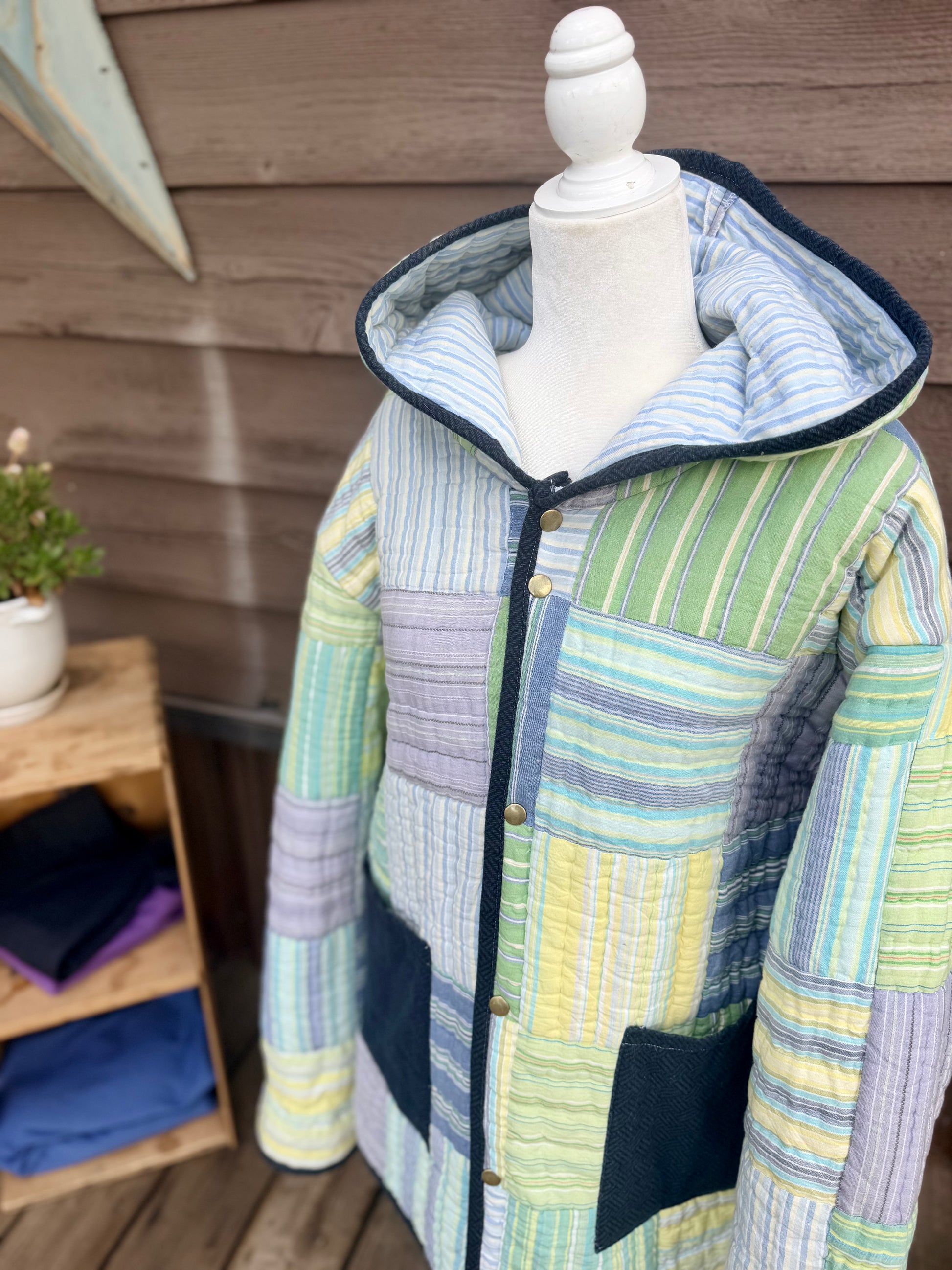 Close-up of the hood and snap front on the striped quilt hooded coat in green, yellow, blue and purple