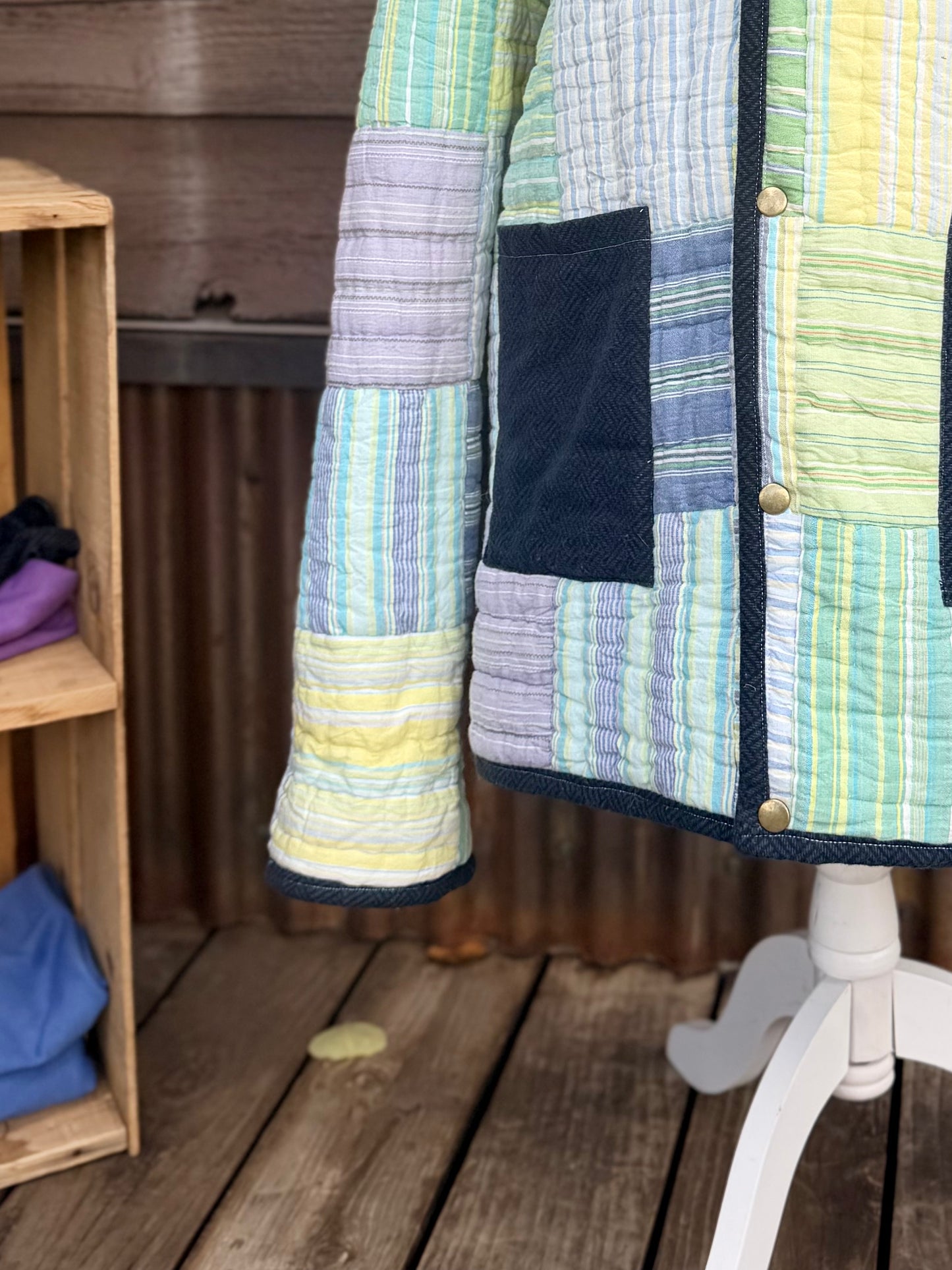 Close-up of the navy wool front pockets on the striped quilt hooded coat in green, yellow, blue and purple