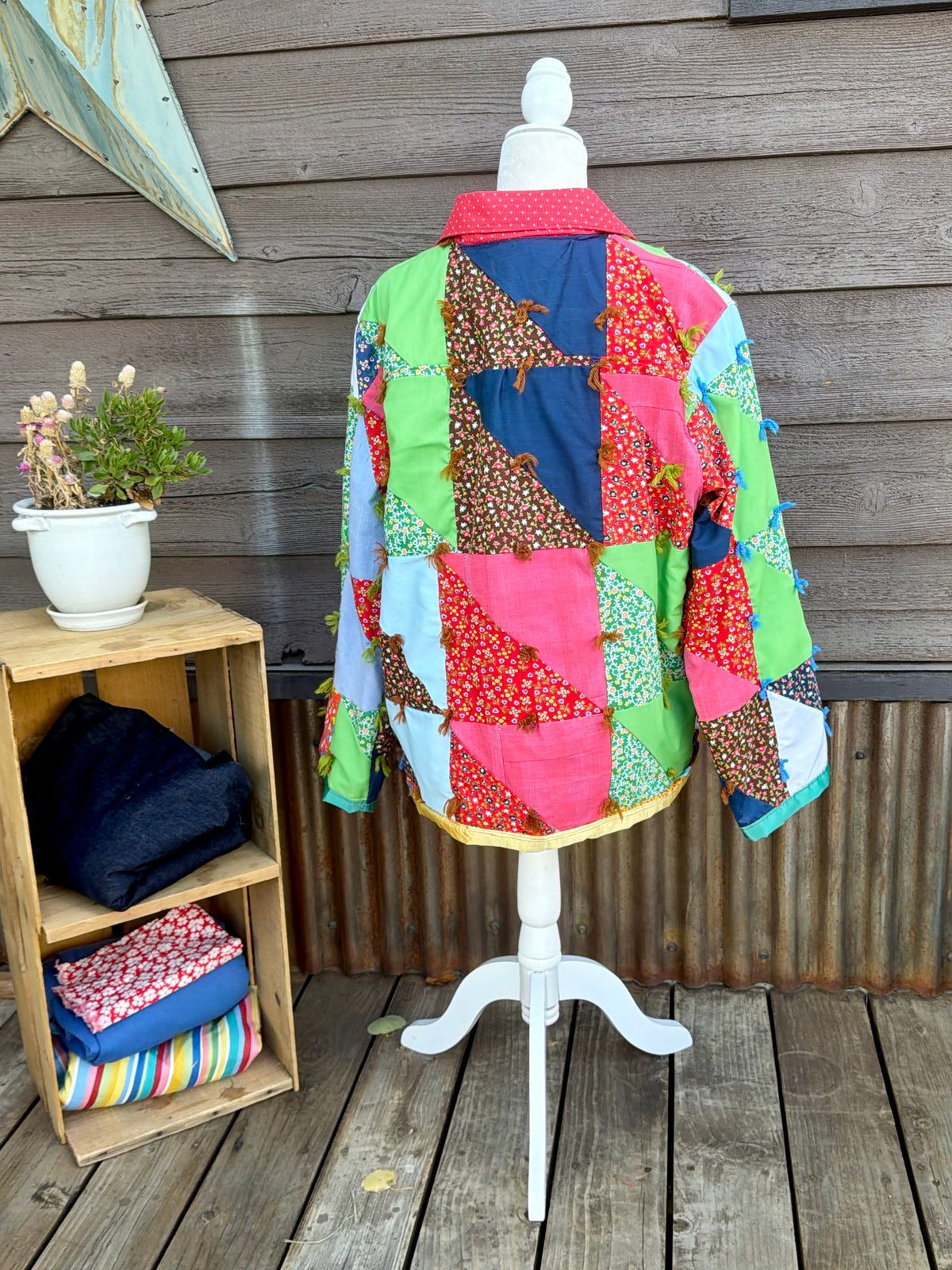 Back of the vintage patchwork quilt camp coat with red collar on a mannequin showing the patchwork quilt back
