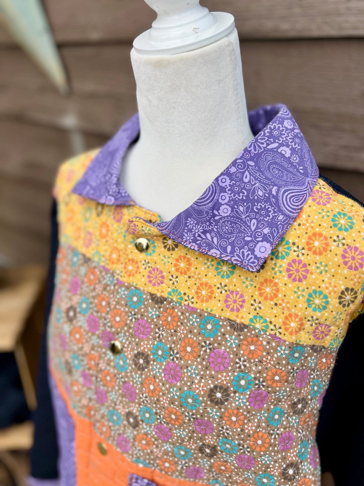 Close-up of the purple collar and snap placket on the yellow quilt camp coat with denim sleeves